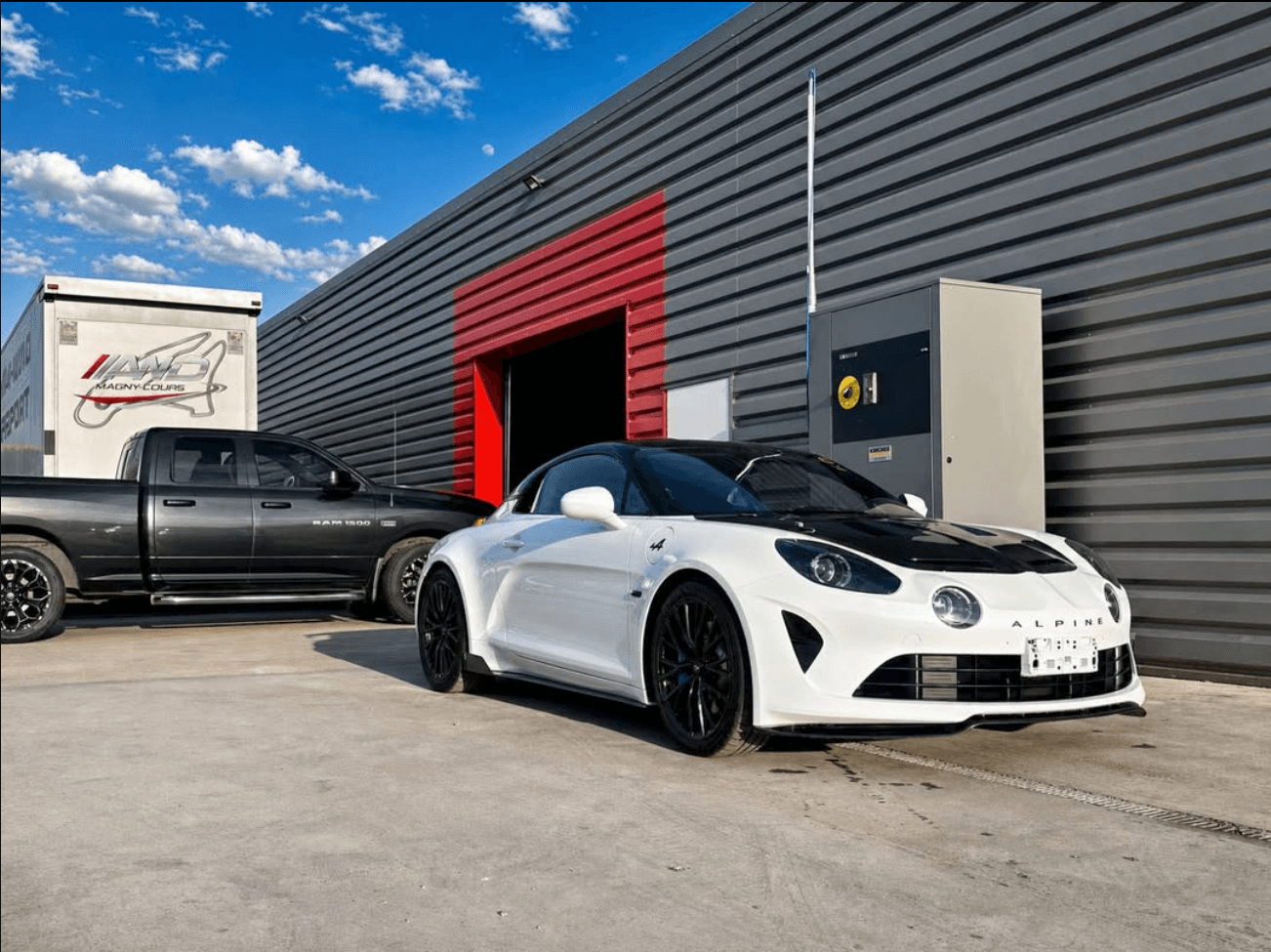 Alpine A110 R blanche devant l'atelier AWD Magny-Cours, protégée par film XPEL sur le pare-chocs avant, les phares et les bas de caisse